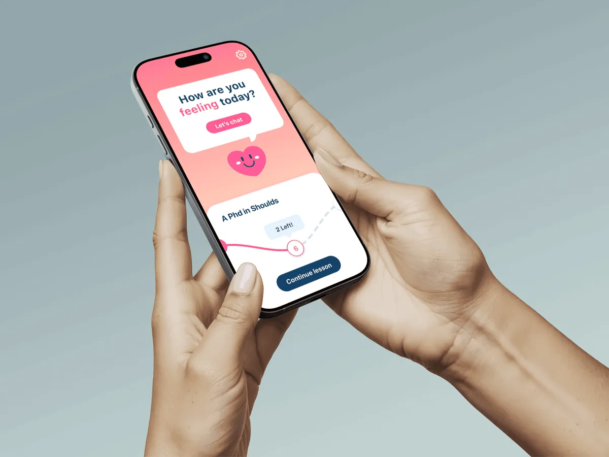A hand holding a phone showing the Feeling Good app: a pink screen that asks how you are feeling today.